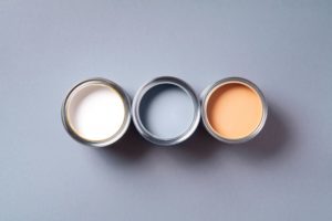 three paint cans sitting next to each other. one is cream, one is gray, and one is peach