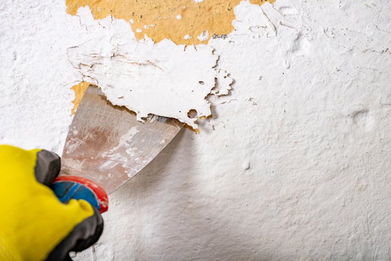 person taking off old house paint