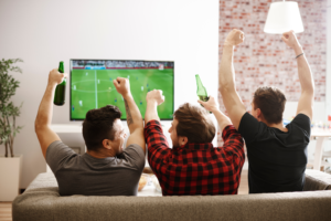 a group of men cheering while watching television 